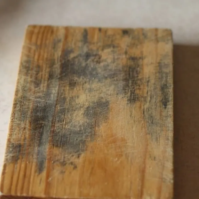 Stained wooden chopping board with dark marks in the grooves